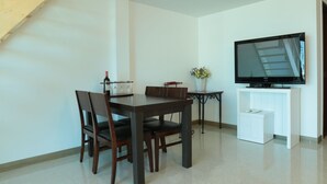 A dining area with a wooden staircase, a television, and a small table with a vase of flowers. - Seaview Pension (Gangneung)