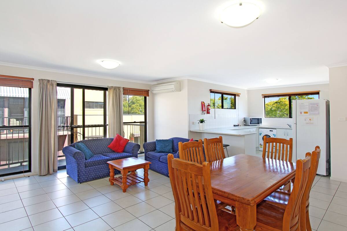 A spacious living area with a dining table and chairs, a sofa, and a kitchen area with a refrigerator and microwave.