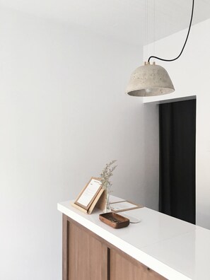 A reception desk with a framed certificate, a small vase with dried flowers, and a wooden tray with coins.