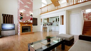 A spacious living area with a fireplace, a television, and a dining table.