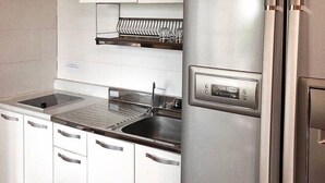 A modern kitchen with stainless steel appliances, white cabinetry, and a built-in dishwasher.