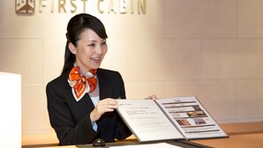 A person at a desk with a menu, in front of a wall with the text "FIRST CABIN". - First Cabin Nagasaki (Nagasaki)