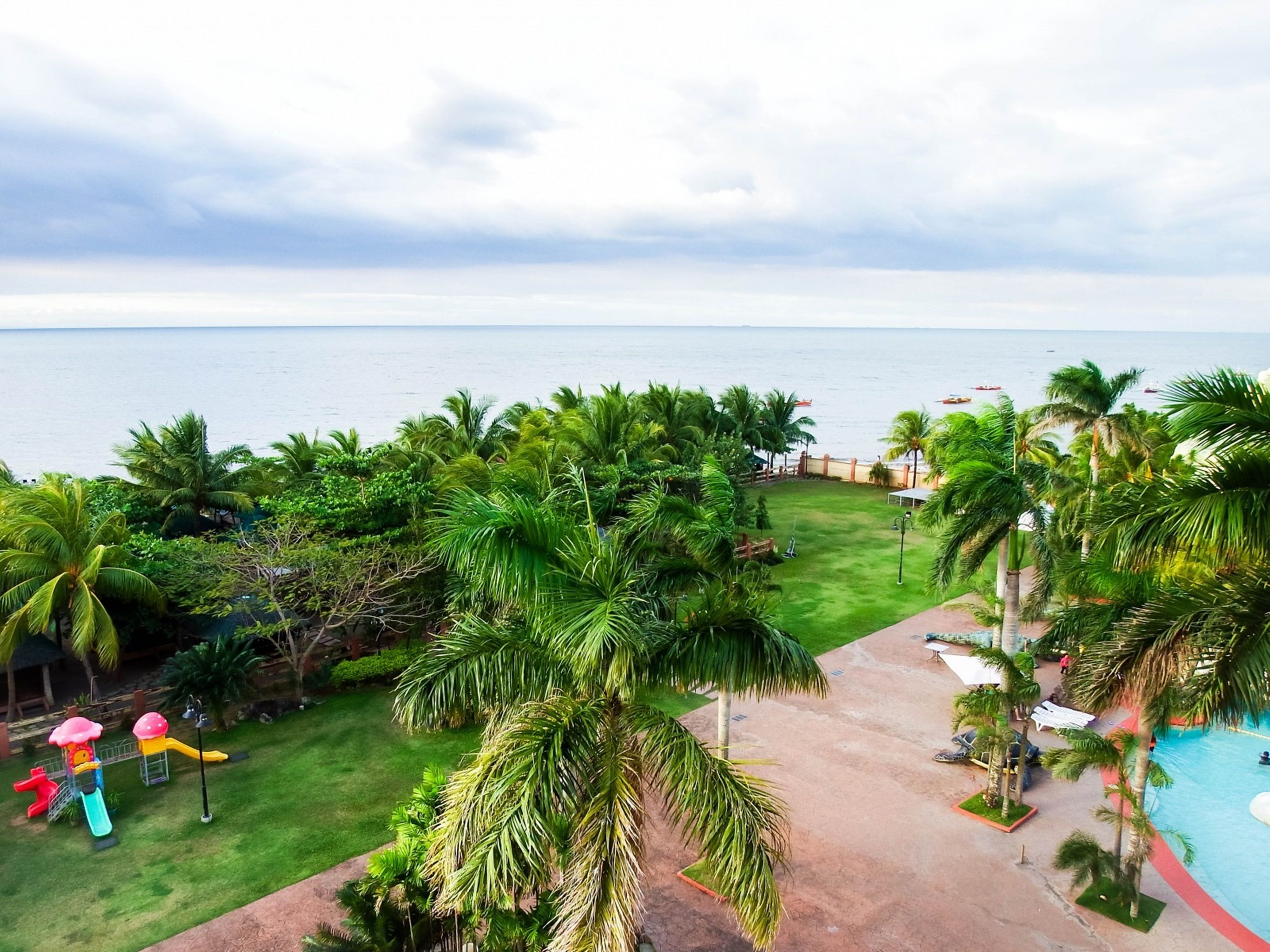 Un resort con piscina, palmeras y vista al océano.