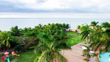 Un resort con piscina, palmeras y vista al océano.