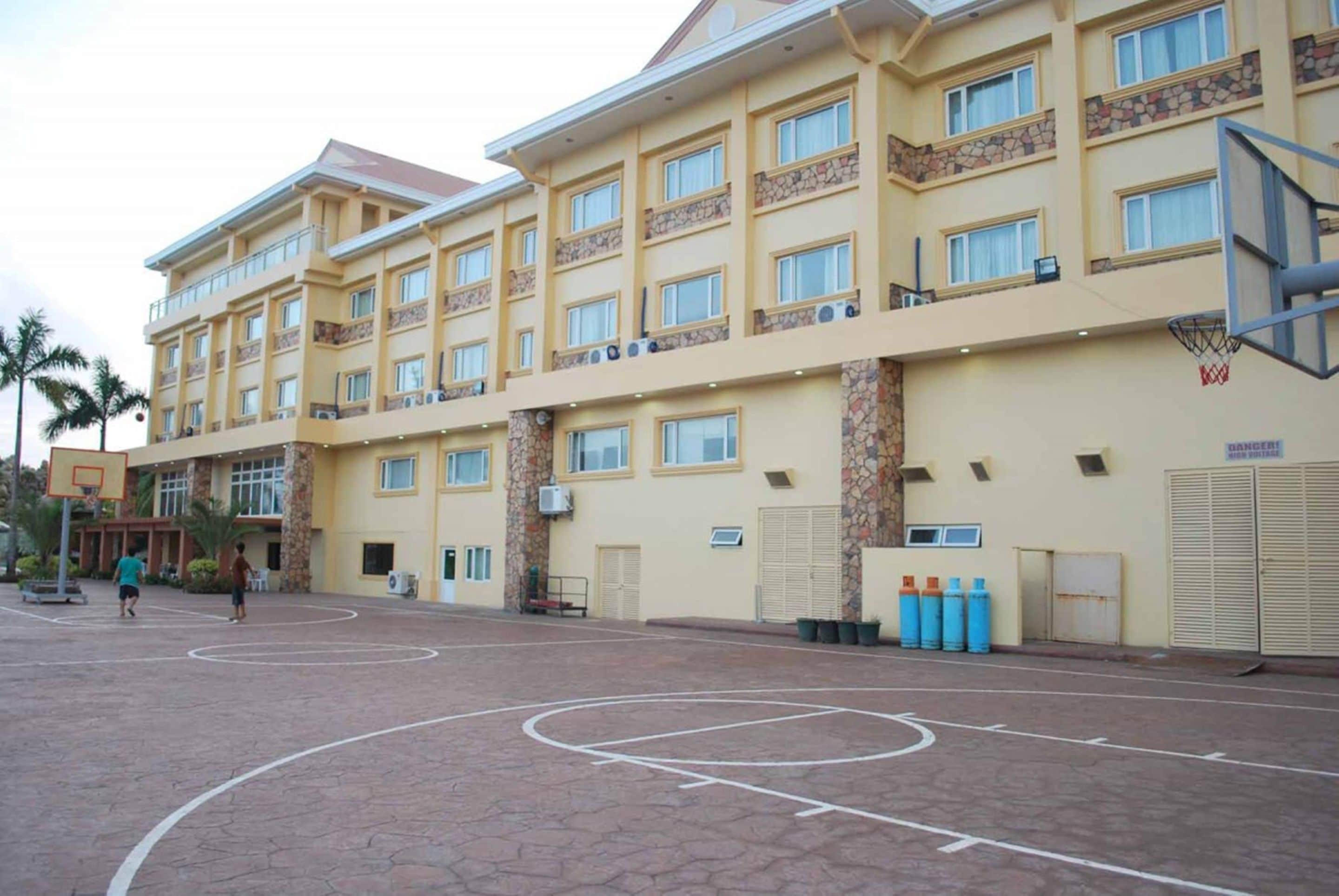 A multi-story hotel with a basketball court in front.