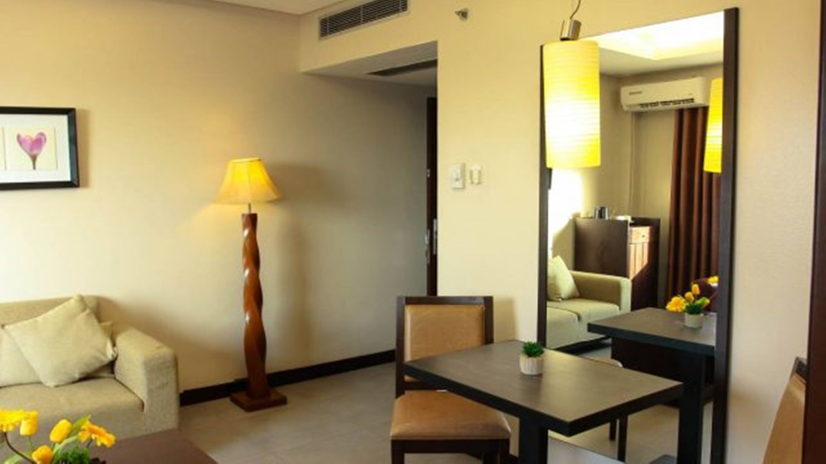 Una habitación de hotel con un sofá, una mesa, una lámpara y un espejo.