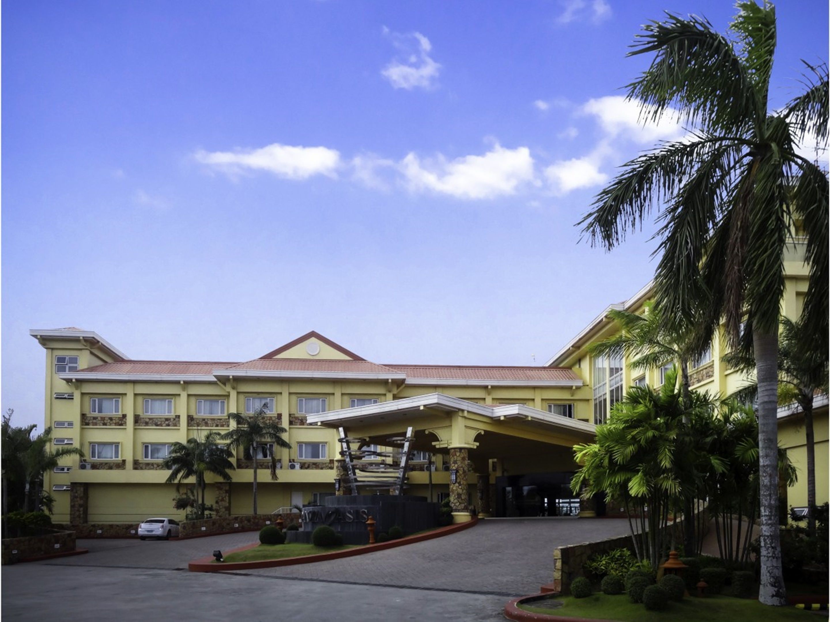 A hotel with a yellow facade, multiple balconies, and a covered entrance.