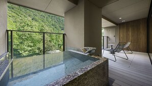 A spa area with a glass-enclosed hot tub, wooden deck, and outdoor seating. - Hatsuhana (Hakone)