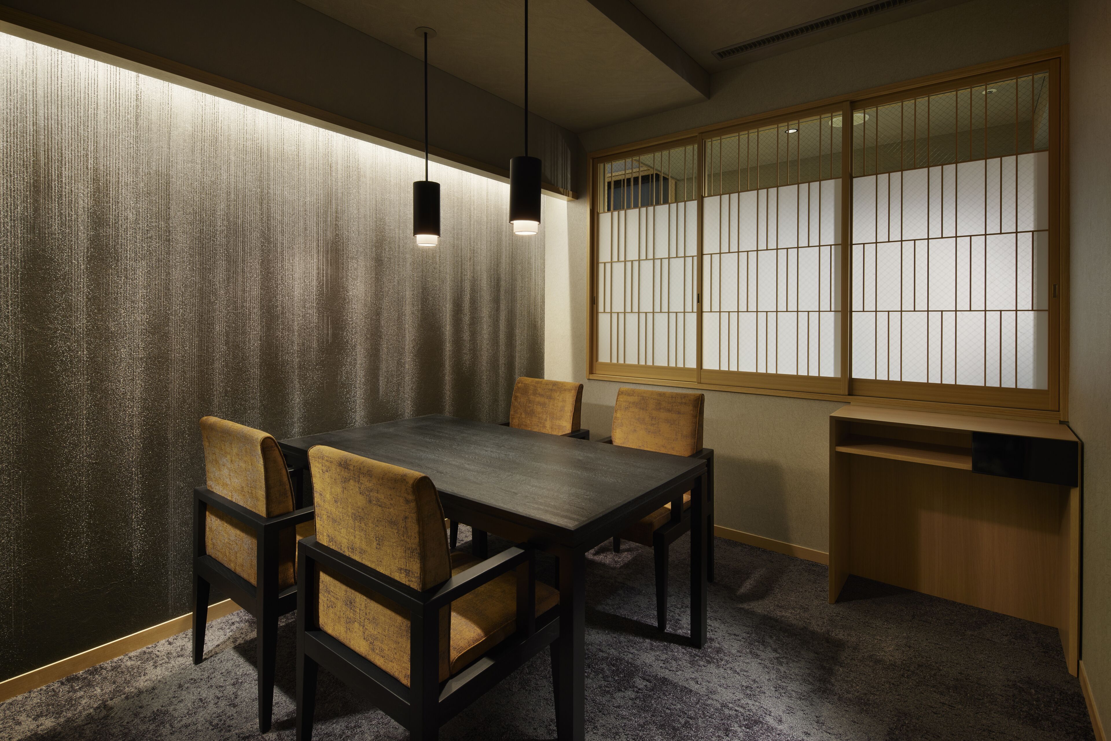 A traditional Japanese room with tatami flooring, a low table with chairs, and a shoji screen with a view.