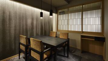 A traditional Japanese room with tatami flooring, a low table with chairs, and a shoji screen with a view.