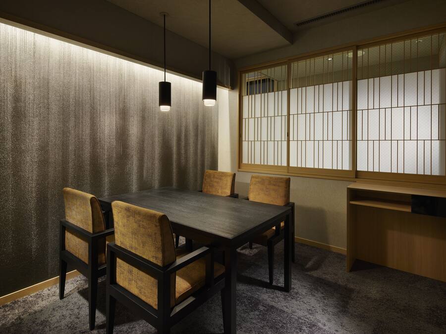 A traditional Japanese room with tatami flooring, a low table with chairs, and a shoji screen with a view.