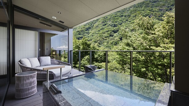 A modern outdoor balcony with a glass infinity pool, a wicker sofa, and a small round table. - Hatsuhana (Hakone)