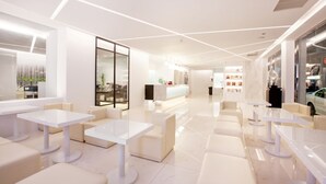 A modern, well-lit lounge area with white tables and sofas, a reception desk, and a glass partition. - Yes Hotel (Taitung)