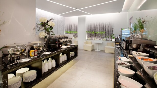 A modern hotel lobby with a reception desk, seating area, and a buffet setup. - Yes Hotel (Taitung)