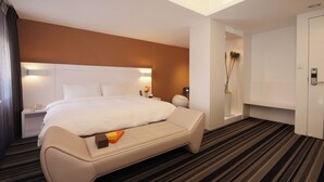 A modern hotel room with a large bed, a bedside table with a lamp, a small seating area, and a wardrobe. - Yes Hotel (Taitung)