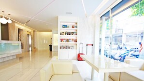 A modern hotel lobby with a reception desk, seating area, and a bookshelf with magazines. - Yes Hotel (Taitung)