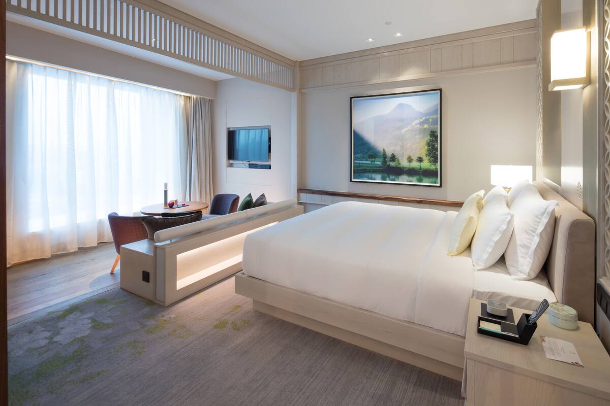 A modern hotel room with a large bed, a desk, and a TV.