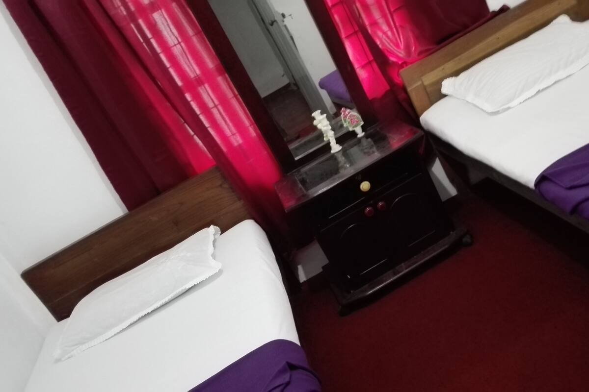 Een hotelkamer met twee eenpersoonsbedden, een houten nachtkastje en een spiegel.