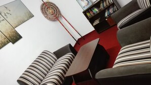 A modern living room with striped sofas, a red carpet, and a bookshelf filled with books. - Kumara Sevana - The Family Cottage (Seetha Eliya)