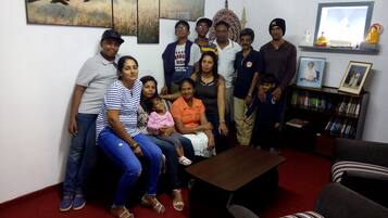 A group of people in a room with a bookshelf, a Buddha statue, and a framed picture on the wall.