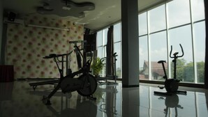 A spacious room with large windows, a ceiling fan, and exercise bikes. - Hotel New Merdeka Pati (Pati)