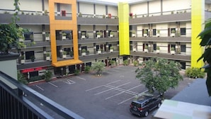 A multi-story hotel with a parking lot and a distinctive orange and yellow facade. - Hotel New Merdeka Pati (Pati)
