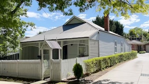 A single-story house with a white picket fence, a covered porch, and a small front yard. - Magnolia cottage Healesville (Healesville)