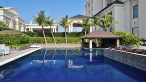 A swimming pool with a tiled deck, lounge chairs, and a gazebo. - Sheraton Grand Palace Indore (Indore)