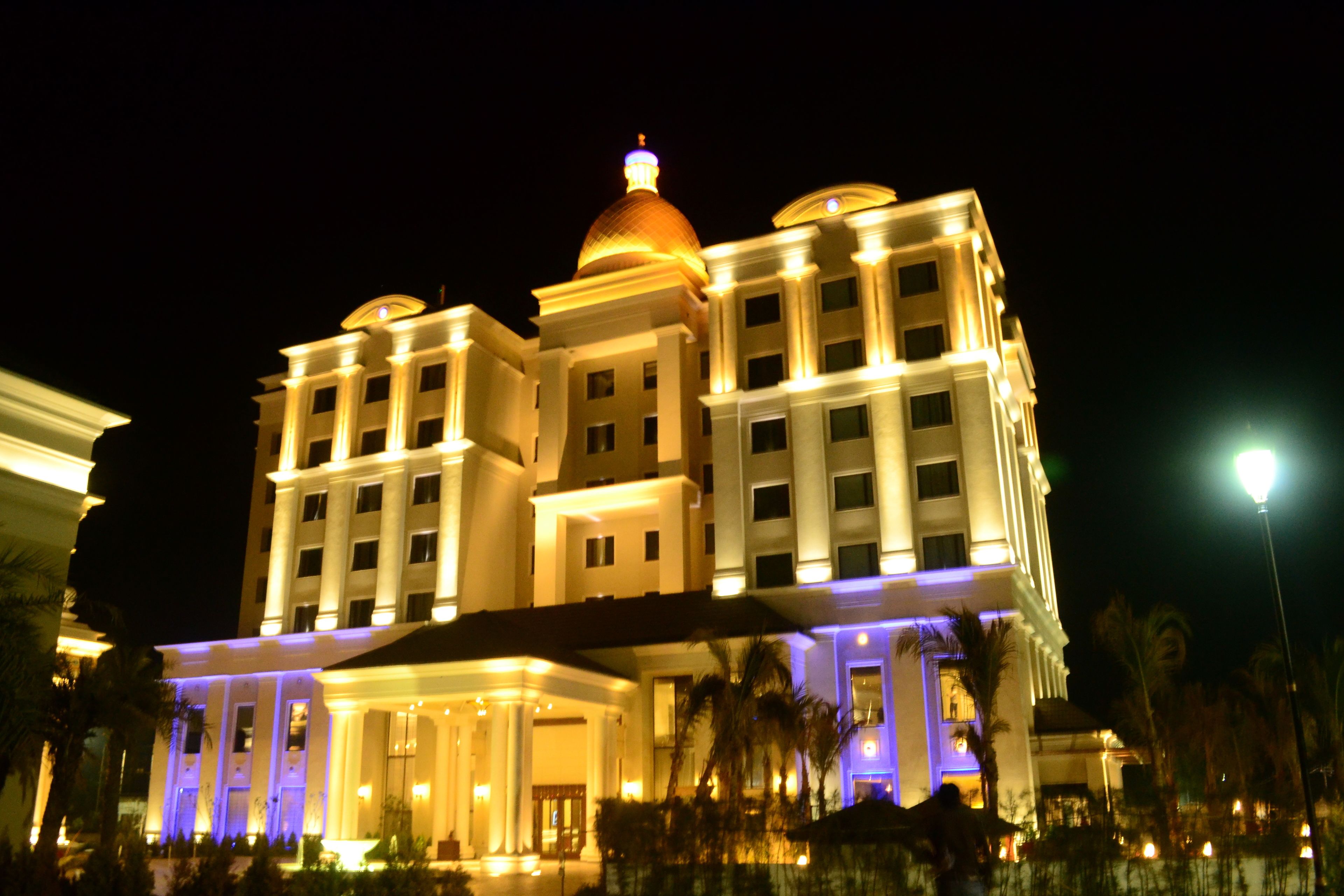 A large, multi-story hotel with a prominent dome and columns, illuminated at night.