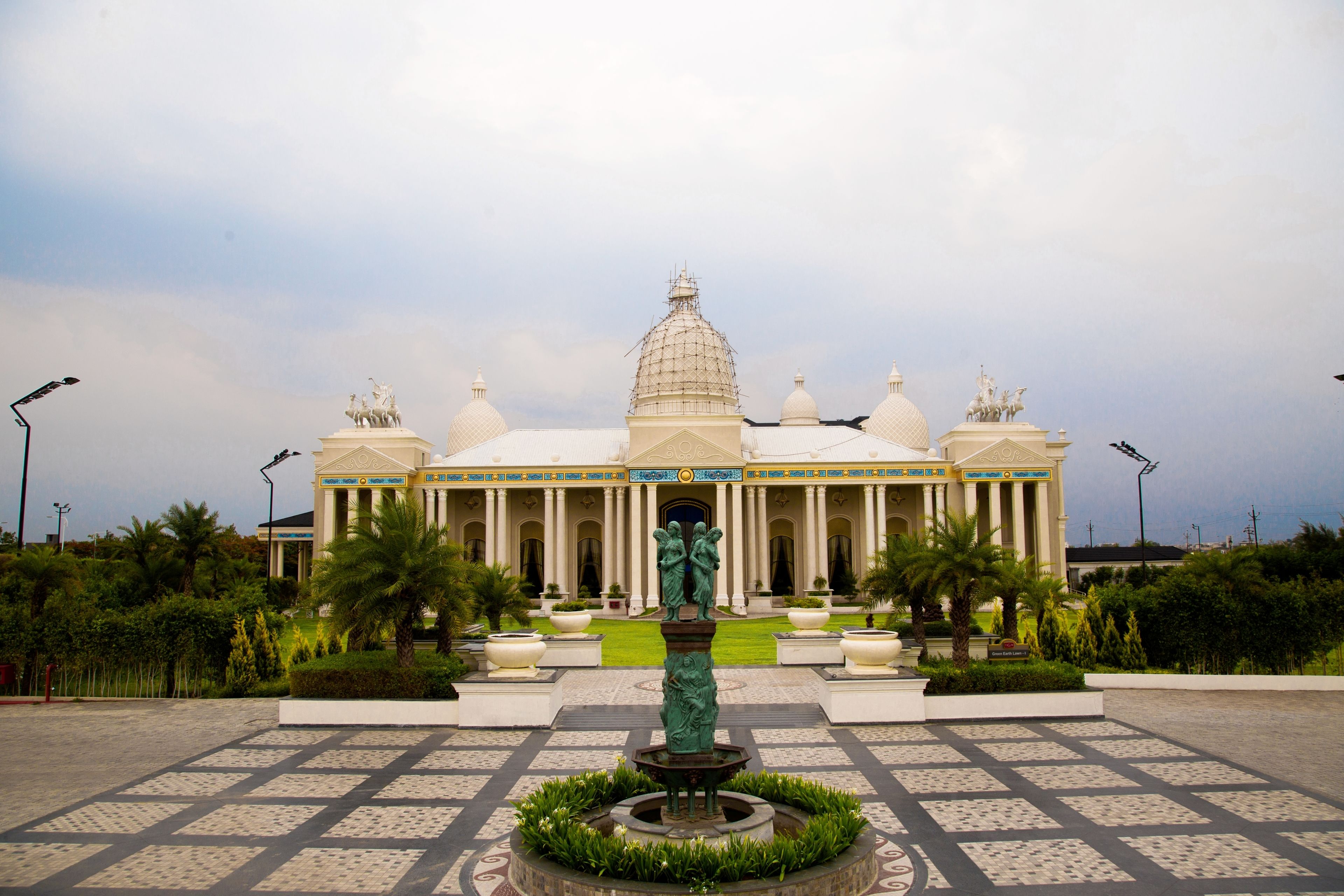 A large building with a central dome and multiple smaller domes, surrounded by a symmetrical garden with a central fountain.