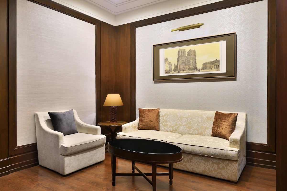 A room with a sofa, a chair, a small table, and a framed picture on the wall.