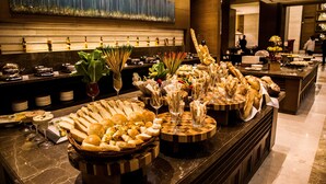 A buffet with various food items and drinks, a large painting on the wall, and a marble countertop. - Sheraton Grand Palace Indore (Indore)
