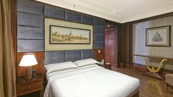 Une chambre d’hôtel avec un grand lit, une table de chevet avec une lampe, un tableau encadré au mur, un bureau en bois et une chaise.