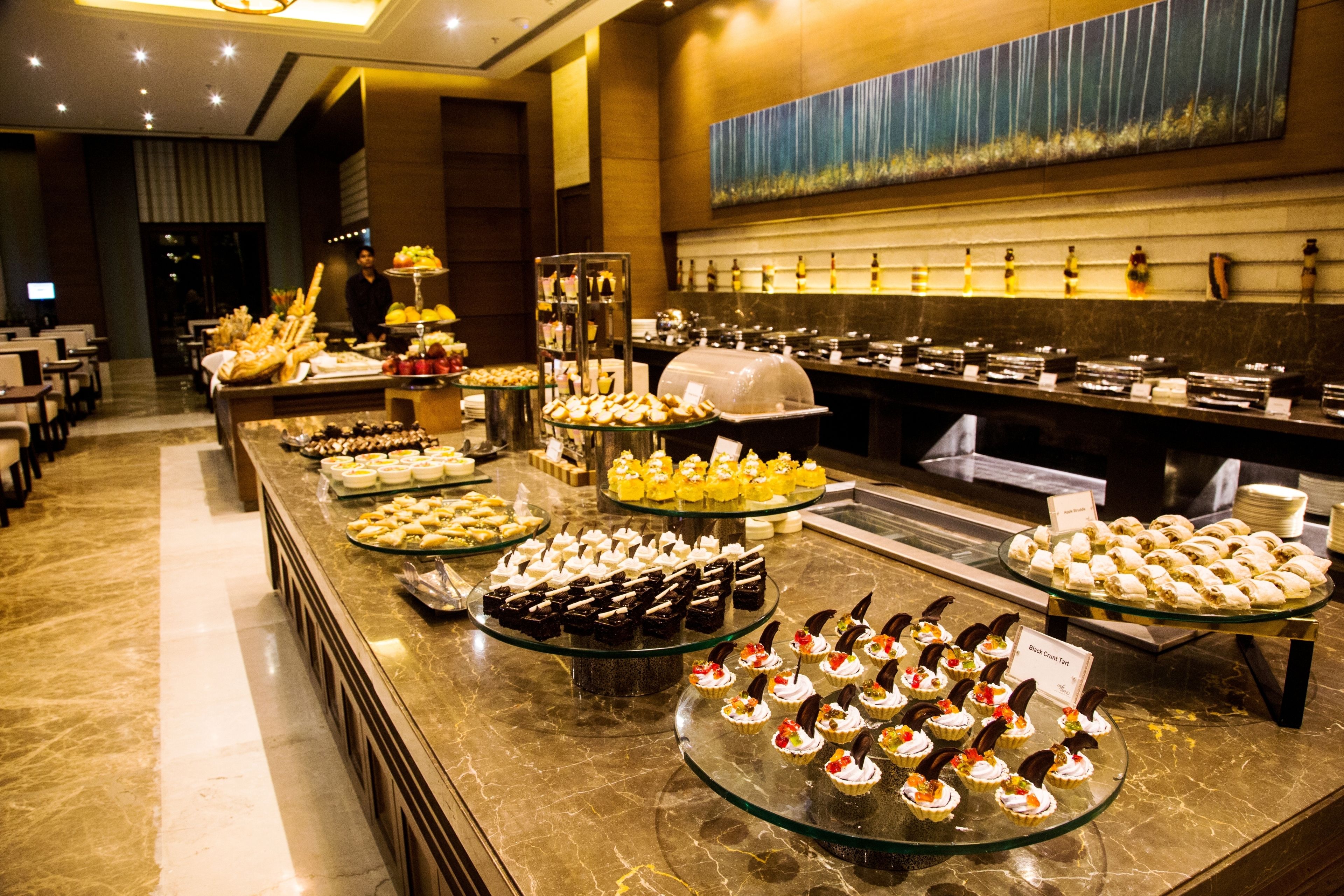 A buffet with various food items and a chef in the background.