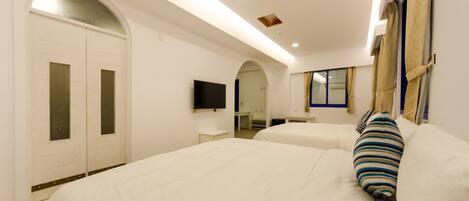 A hotel room with two beds, a TV, a desk, and a bathroom.