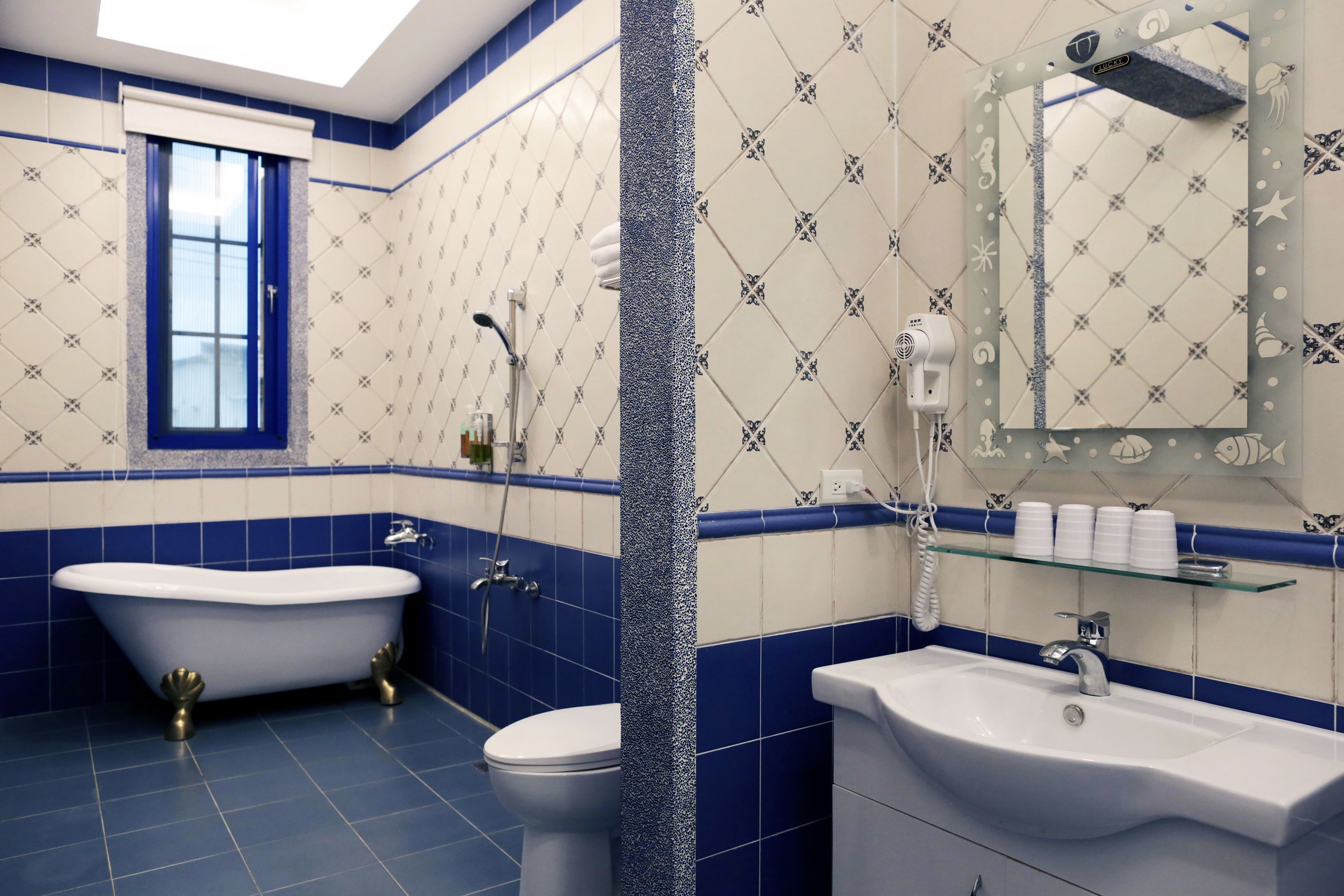 A bathroom with a freestanding bathtub, a toilet, a sink, and a mirror with a shelf above it.