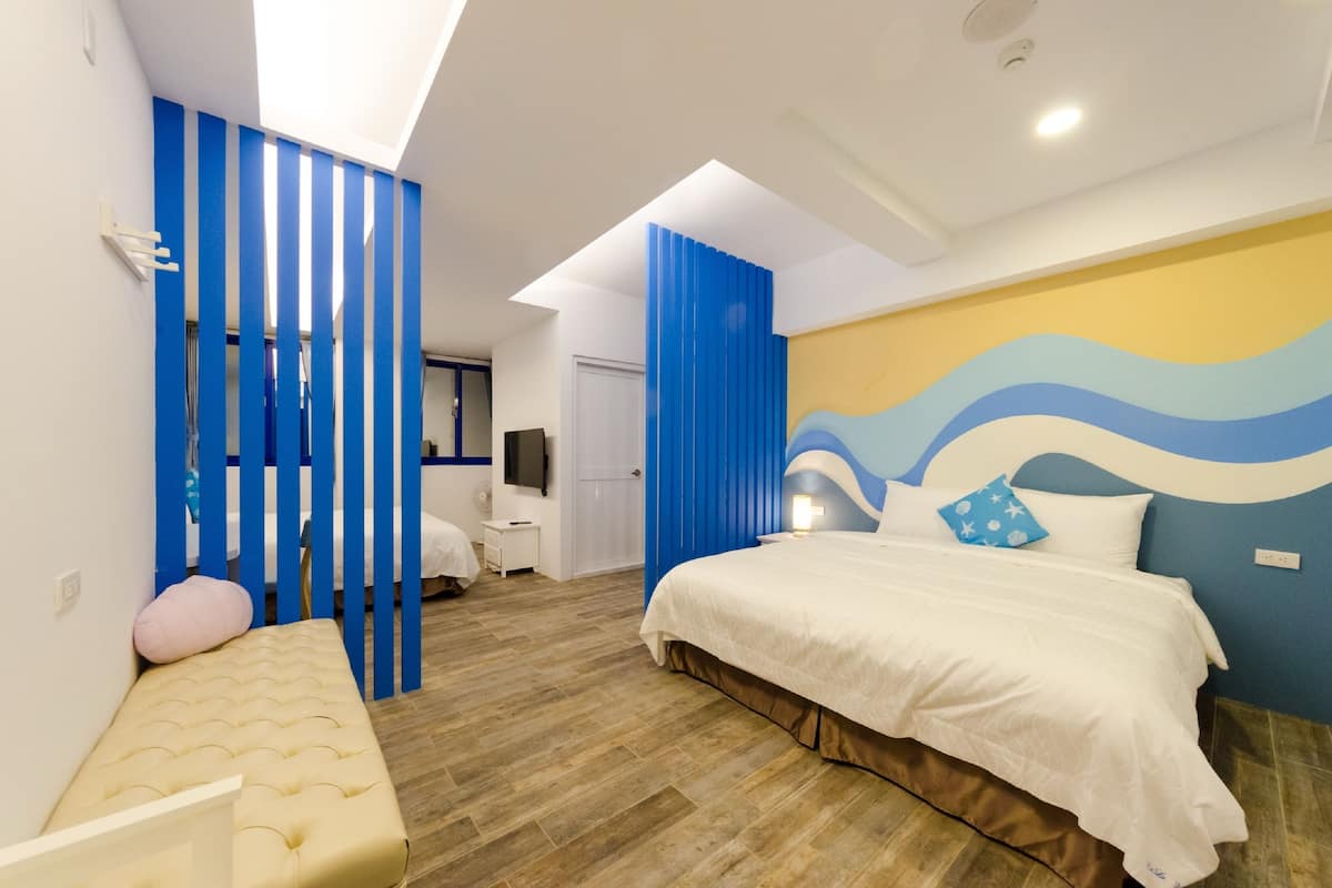 A modern bedroom with a large bed, a bench, and a TV.