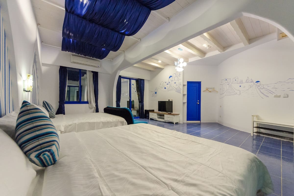 A bedroom with two beds, a TV, and a mural on the wall.