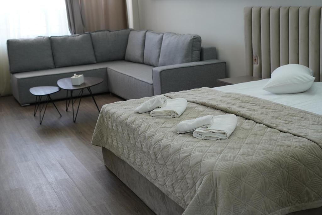 Une chambre d’hôtel avec un lit, un canapé, une petite table et un radiateur.