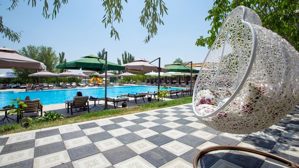 A poolside area with checkered flooring, lounge chairs, and umbrellas. - Cross Health Center (Yerevan)