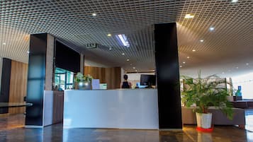 A modern reception area with a reception desk, a potted plant, and a seating area with a sofa.
