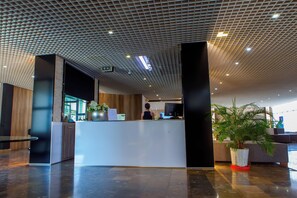 A modern reception area with a reception desk, a potted plant, and a seating area with a sofa. - Cross Health Center (Yerevan)