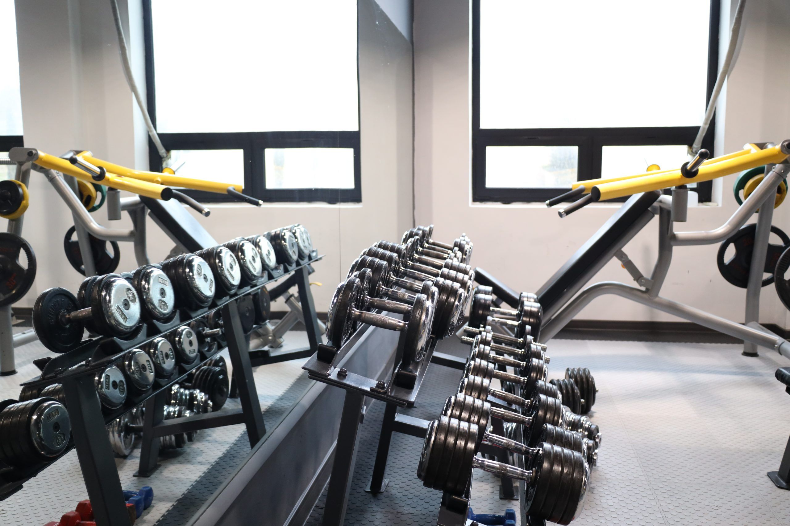 Een sportschool met gewichthefapparatuur, waaronder dumbbells en barbells, geordend op rekken.