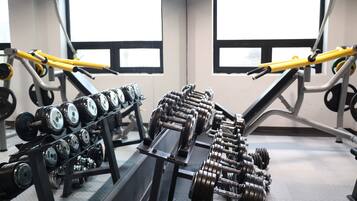 Een sportschool met gewichthefapparatuur, waaronder dumbbells en barbells, geordend op rekken.