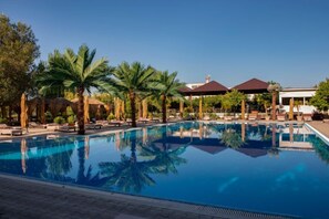A swimming pool with lounge chairs and palm trees. - Cross Health Center (Yerevan)