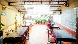 An indoor dining area with tables and chairs, potted plants, and a tiled wall. - Hotel Lucky Bandra (Mumbai)