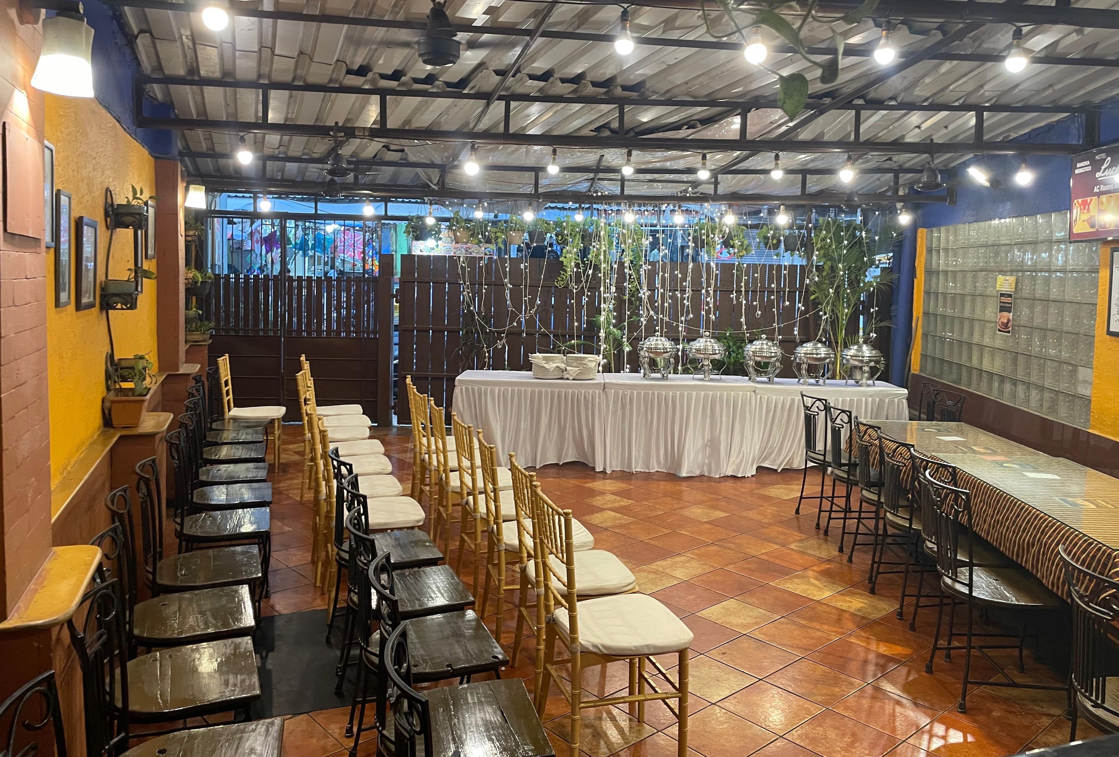 A restaurant with long tables and chairs, a stage, and decorative lighting.