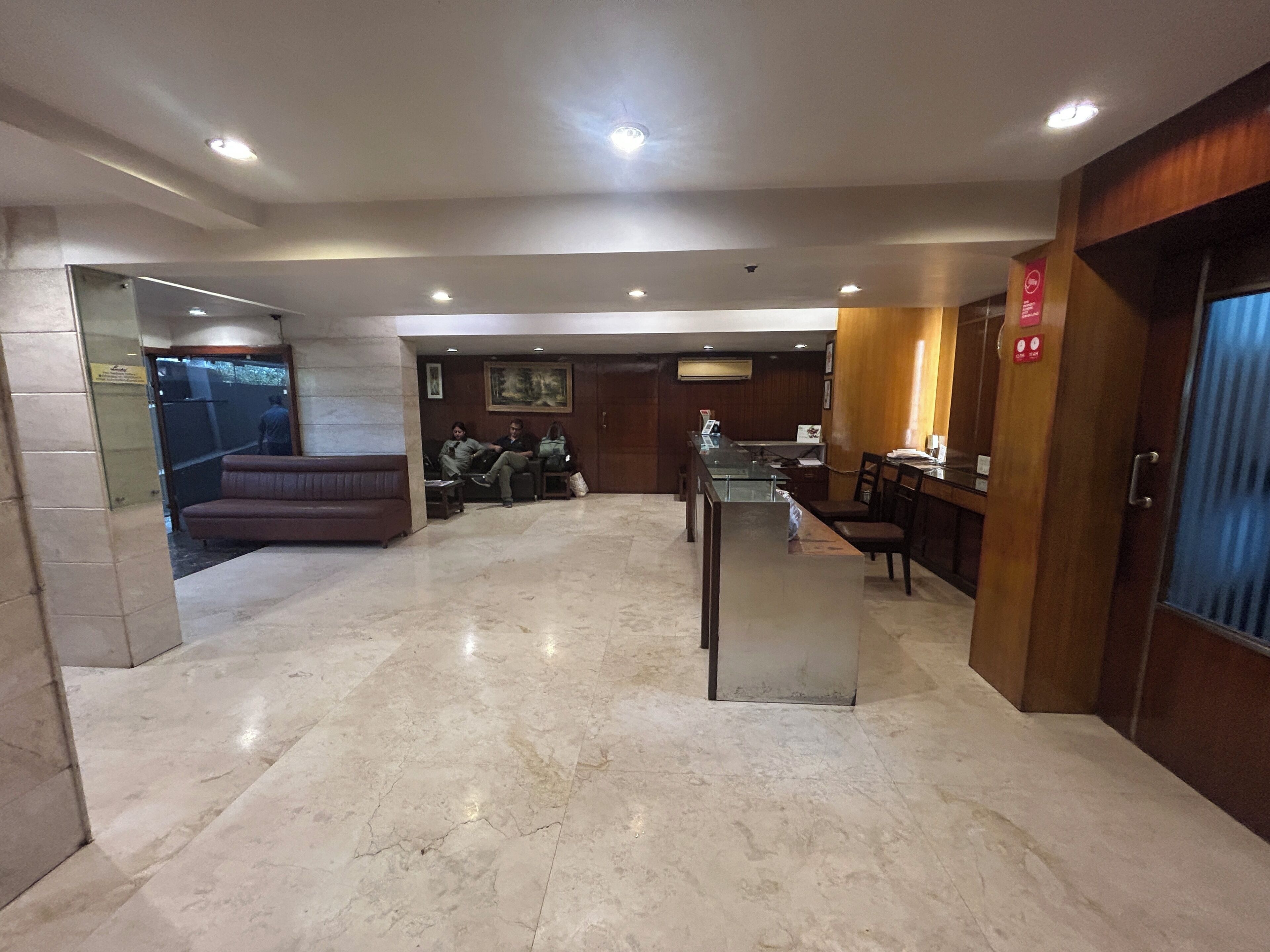 A lobby with a reception desk, seating area, and a door leading to another room.