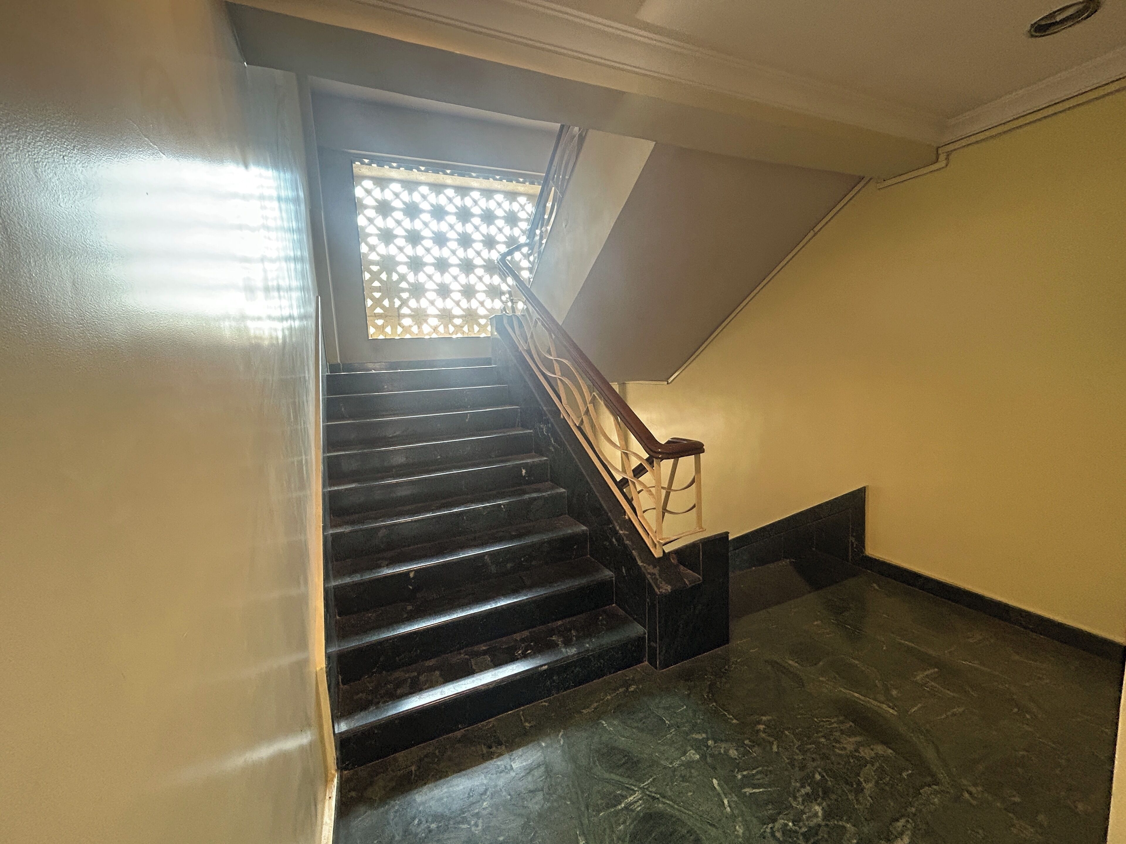 A staircase with a wooden handrail and black steps leading to a landing.