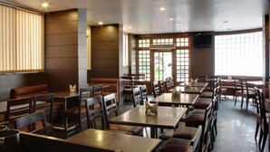 Un restaurante con cabinas y mesas, ventanas amplias y un techo plano.